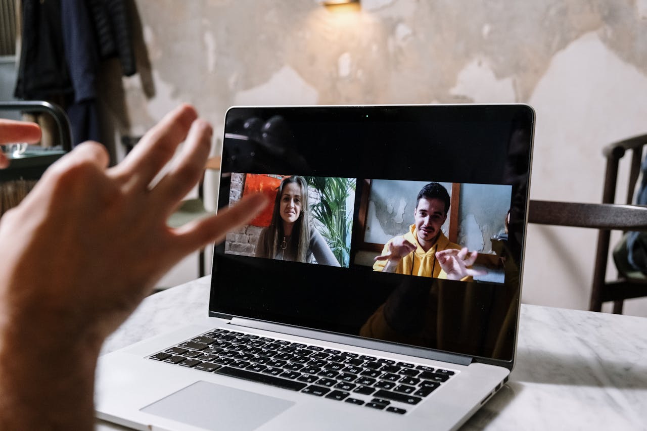 Why Internet Telephony is Essential to Your Business Technology Strategy a team member sitting at a laptop, speaking on video call with their colleagues. Showing a business using modern internet telephony systems.