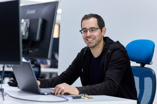 Our customer success team working at a desk, sitting on a blue desk chair. CYAN IT Service Provider