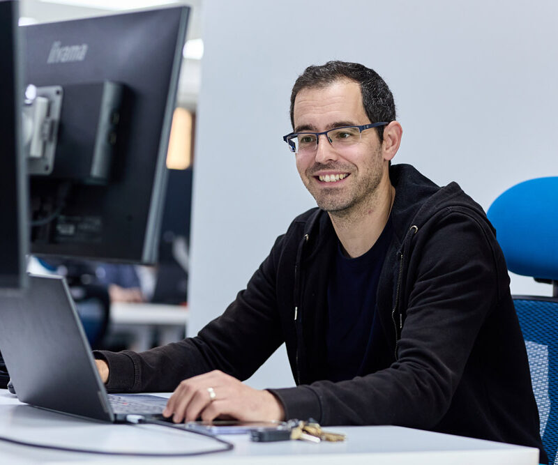 Our customer success team working at a desk, sitting on a blue desk chair. CYAN IT Service Provider