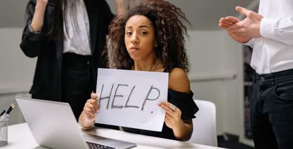 5 Signs You Need A New IT Provider a woman holding up a paper sign 'help' feeling helpless and lost due to not having a clear IT strategy