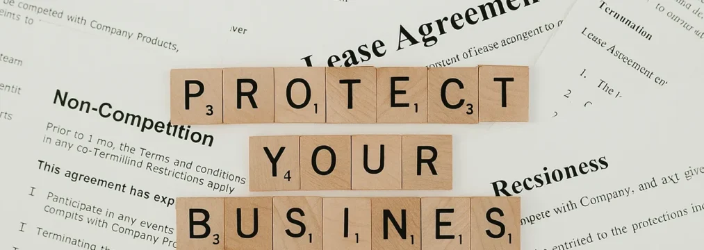 What You Need to Include in an AI Policy A variety of policy documents spread across a table, with scrabble pieces reading 'protect your business'. ai policy template for business